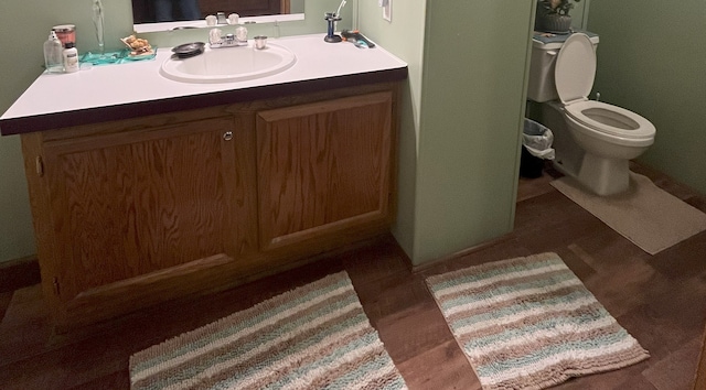 bathroom featuring toilet, vanity, and hardwood / wood-style floors