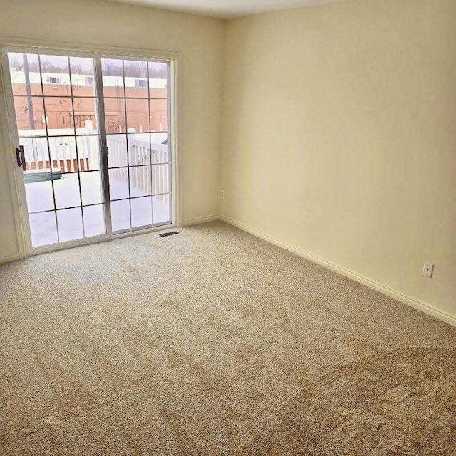 spare room featuring carpet, visible vents, and baseboards