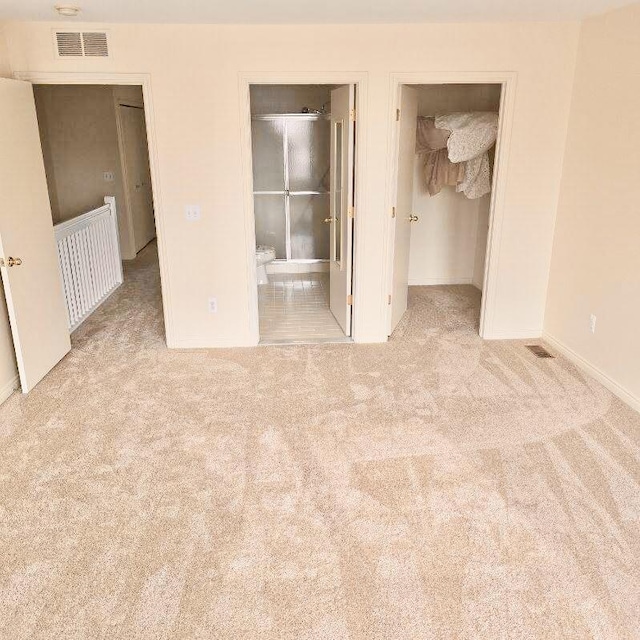 unfurnished bedroom featuring a closet, light carpet, visible vents, and a spacious closet