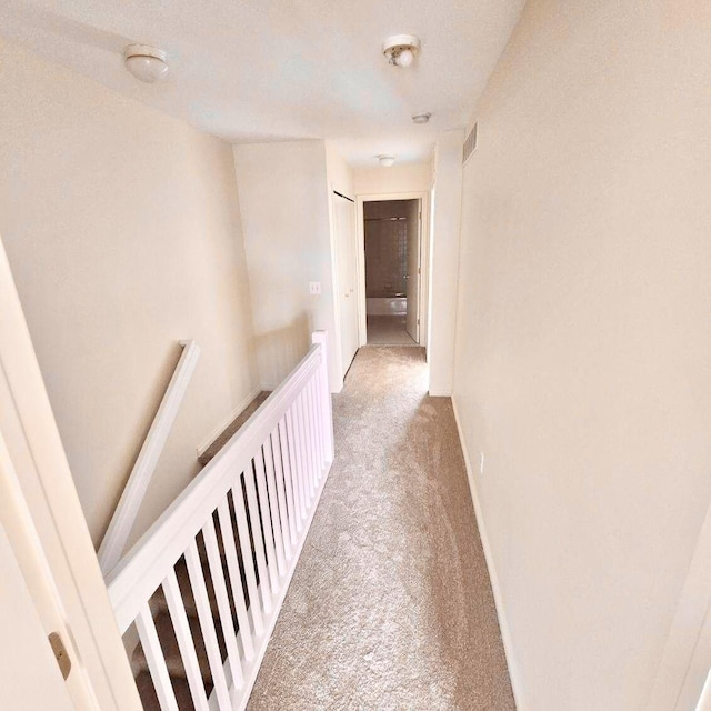 hall featuring baseboards, carpet flooring, visible vents, and an upstairs landing