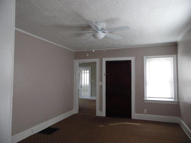 empty room featuring a textured ceiling, ceiling fan, and ornamental molding