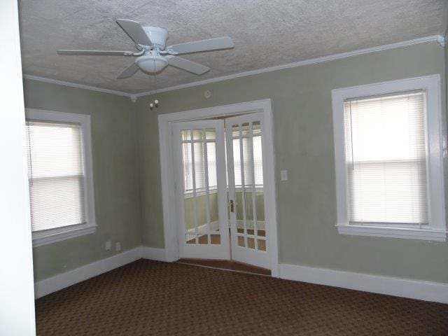 empty room featuring ceiling fan, plenty of natural light, ornamental molding, and french doors