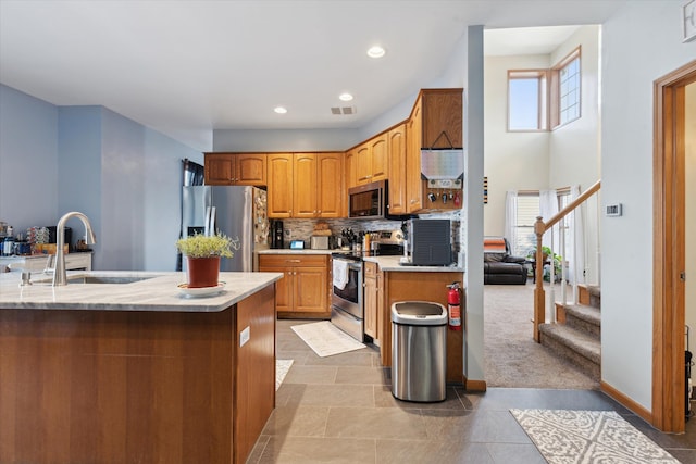 kitchen with sink, backsplash, light colored carpet, and appliances with stainless steel finishes