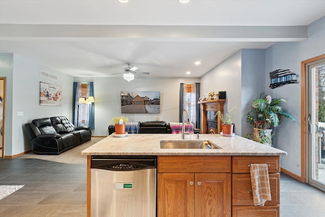 kitchen with light stone countertops, dishwasher, sink, ceiling fan, and a center island with sink