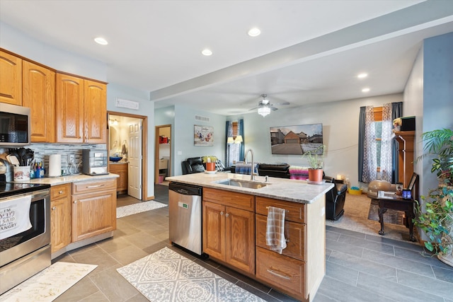 kitchen featuring stainless steel appliances, an island with sink, sink, light tile patterned flooring, and ceiling fan