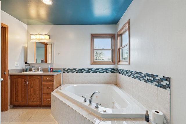 bathroom with tile patterned flooring, tiled tub, and vanity