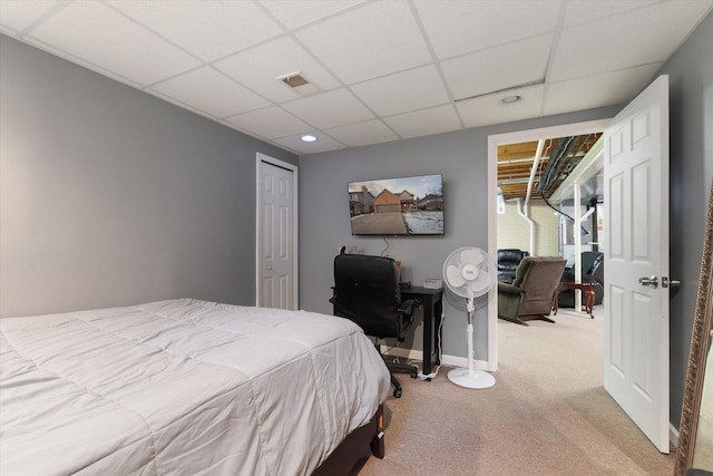 bedroom featuring light carpet, a paneled ceiling, and a closet