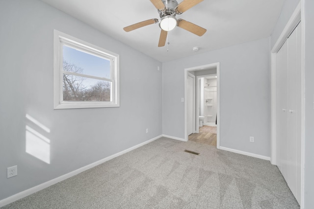 unfurnished bedroom featuring ceiling fan, light colored carpet, and a closet