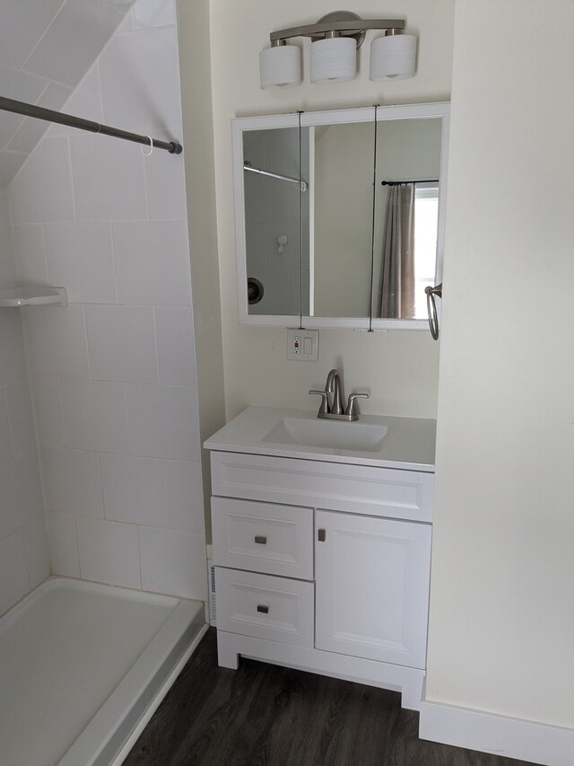 bathroom with hardwood / wood-style flooring, vanity, and a shower