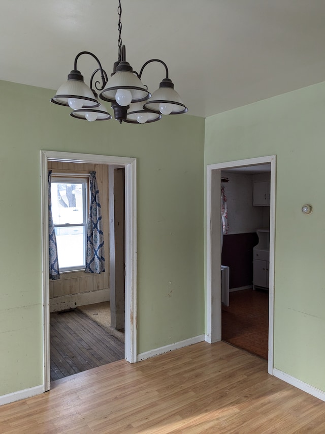 unfurnished dining area with light hardwood / wood-style floors and a notable chandelier