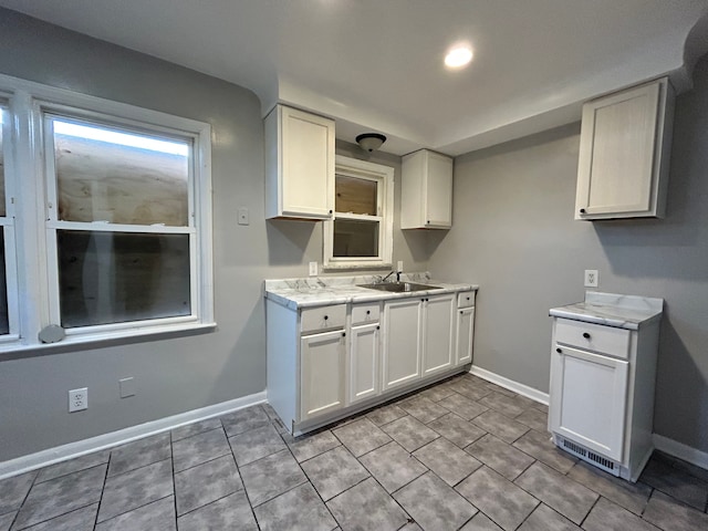 kitchen featuring sink, white cabinetry, and light tile patterned floors