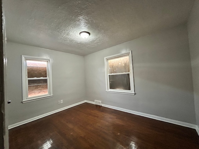 spare room featuring wood-type flooring and a textured ceiling