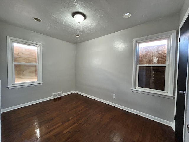 unfurnished room with dark wood-type flooring and a textured ceiling