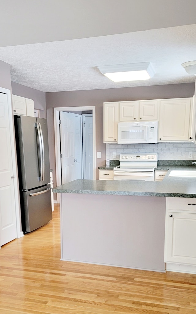 kitchen with sink, tasteful backsplash, light wood-type flooring, white appliances, and white cabinets