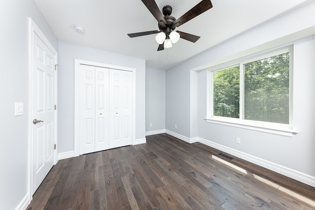 unfurnished bedroom with dark wood-type flooring, ceiling fan, and a closet