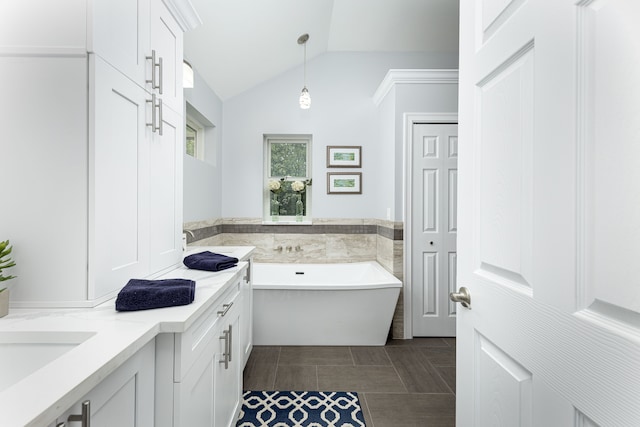 bathroom with tile patterned floors, vanity, a bathing tub, and vaulted ceiling