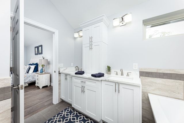 bathroom with a bathing tub, lofted ceiling, and vanity