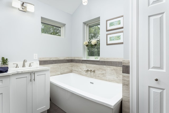 bathroom featuring vanity, a bathing tub, and vaulted ceiling