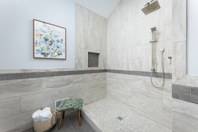 bathroom with tile patterned flooring and a tile shower