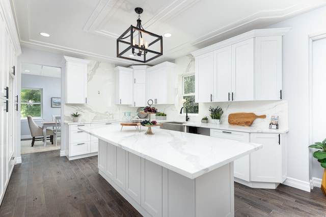 kitchen with white cabinetry, backsplash, pendant lighting, light stone counters, and a center island