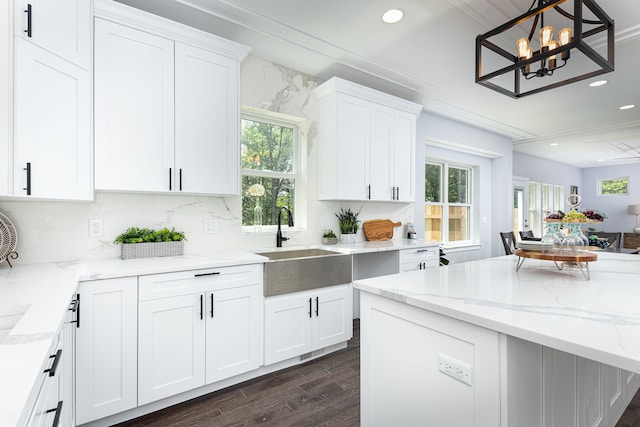 kitchen with a healthy amount of sunlight, dark wood-type flooring, white cabinetry, and pendant lighting