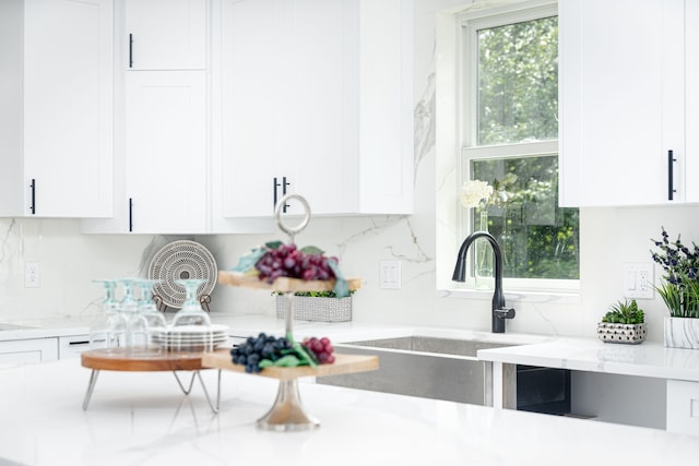 kitchen with light stone countertops, sink, and white cabinets