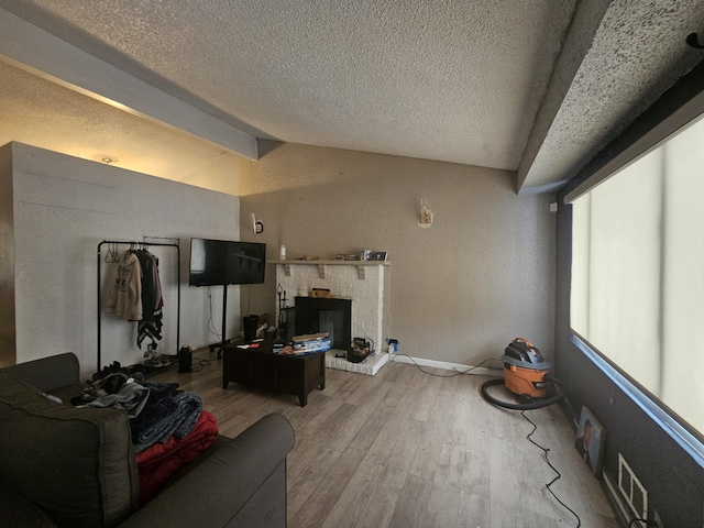 living room with lofted ceiling, wood-type flooring, a brick fireplace, and a textured ceiling