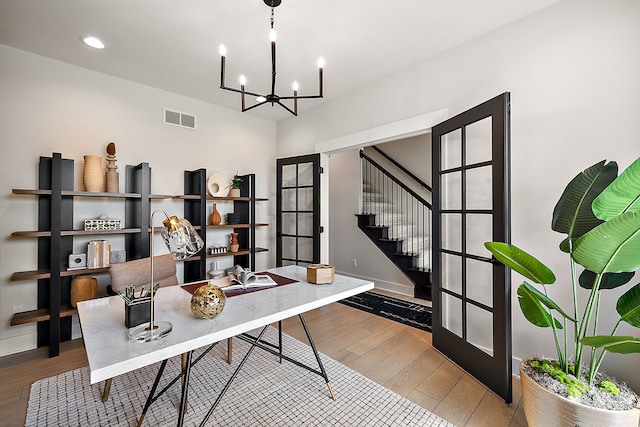 home office featuring wood-type flooring, a notable chandelier, and french doors