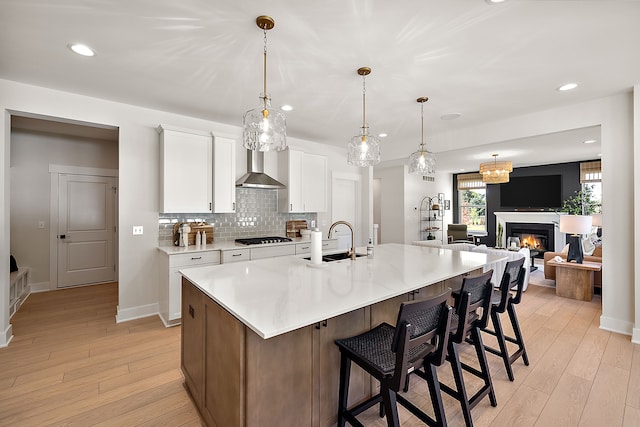 kitchen with a spacious island, white cabinets, black gas stovetop, sink, and hanging light fixtures