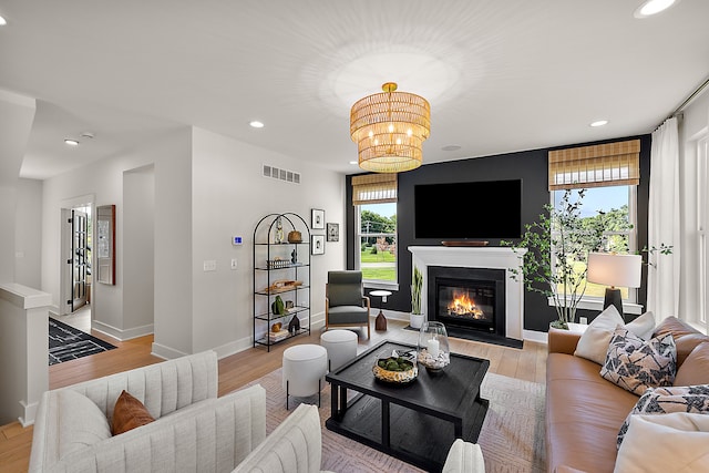 living room with a wealth of natural light, a chandelier, and light hardwood / wood-style flooring