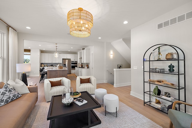 living room featuring light wood-type flooring and a notable chandelier