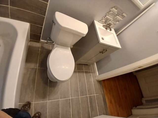 bathroom featuring toilet and a tub to relax in