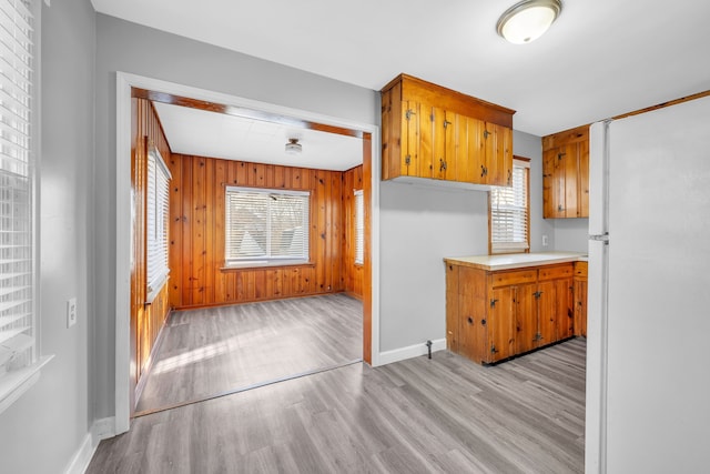 kitchen with light wood-type flooring, wood walls, and white fridge