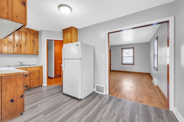 kitchen with sink, white refrigerator, and light hardwood / wood-style flooring