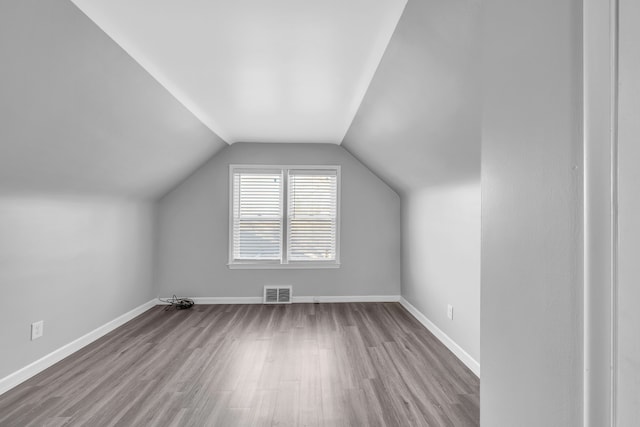 additional living space with light hardwood / wood-style floors and lofted ceiling