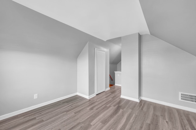 additional living space with light wood-type flooring and lofted ceiling