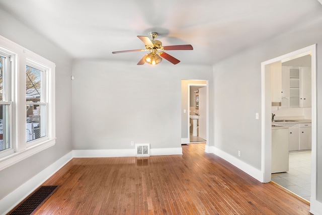 unfurnished room with ceiling fan, sink, and light wood-type flooring