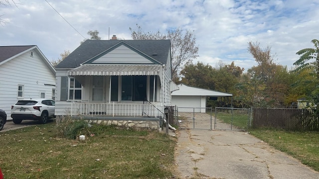 bungalow with covered porch, a front yard, and a garage