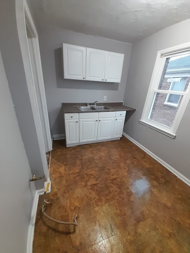 kitchen with sink, a textured ceiling, and white cabinets