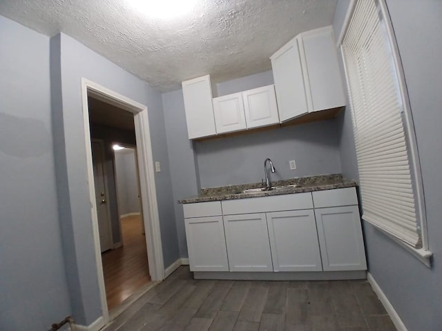 kitchen featuring sink, dark wood-type flooring, white cabinetry, and a textured ceiling