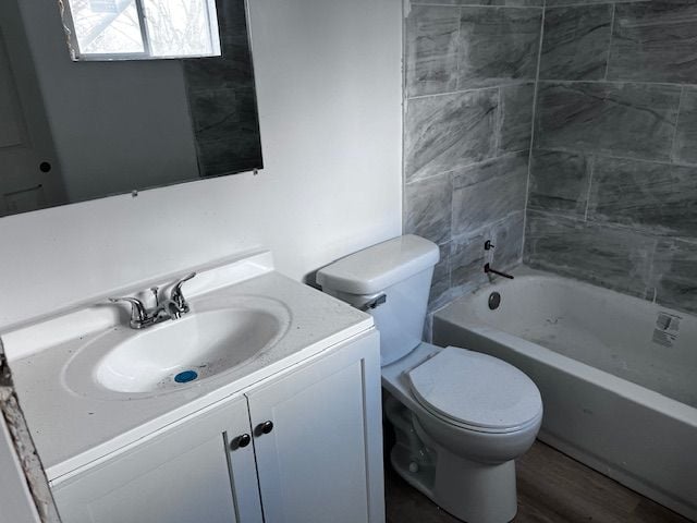 full bathroom featuring toilet, vanity, tiled shower / bath combo, and hardwood / wood-style floors