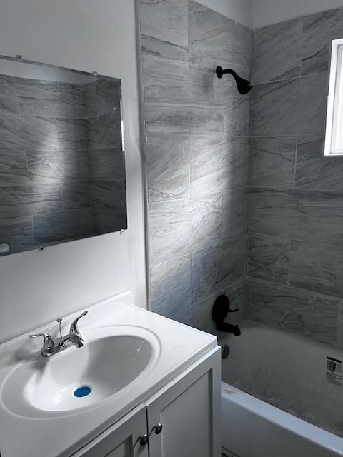 bathroom featuring tiled shower / bath combo and vanity