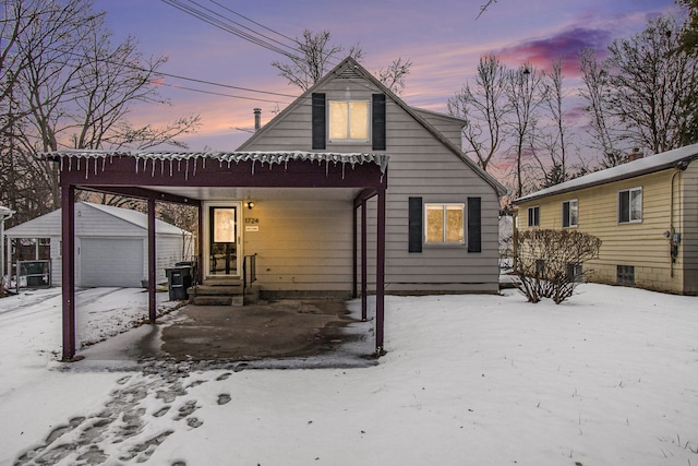 snow covered property with a garage and an outbuilding