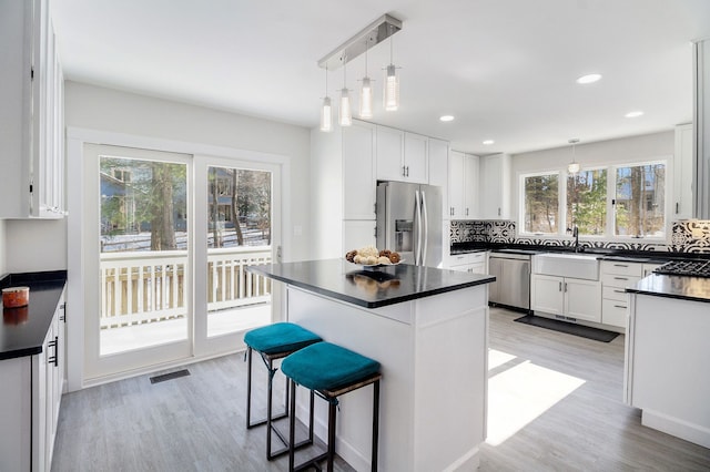 kitchen with white cabinetry, pendant lighting, a breakfast bar, and appliances with stainless steel finishes