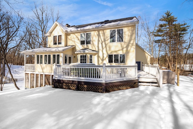 snow covered back of property featuring a deck