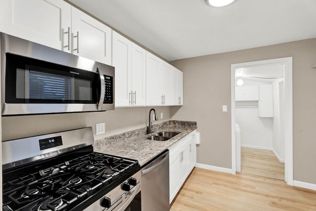 kitchen with light stone counters, sink, white cabinetry, and stainless steel appliances