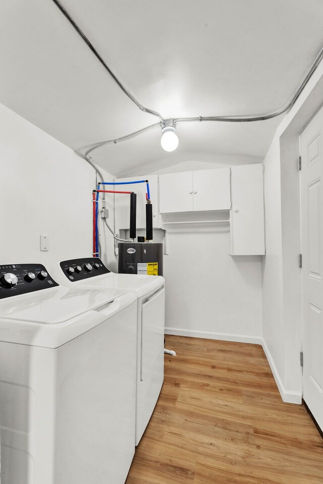 laundry area with electric water heater, washing machine and dryer, and light hardwood / wood-style floors