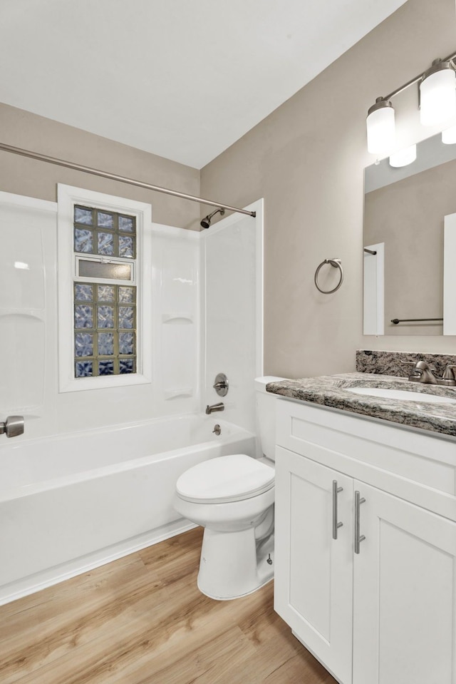 full bathroom with hardwood / wood-style flooring, vanity, shower / washtub combination, and toilet