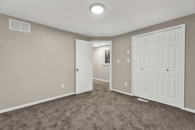 unfurnished bedroom featuring dark carpet and a closet