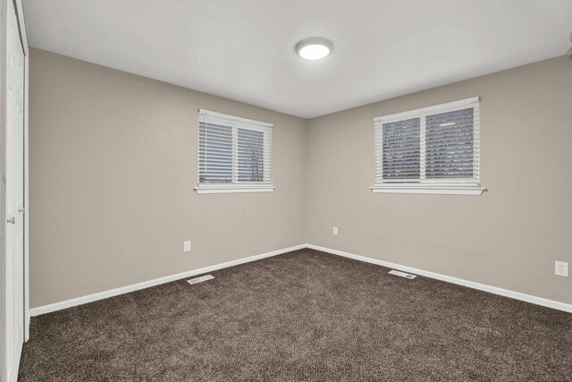 spare room featuring dark colored carpet